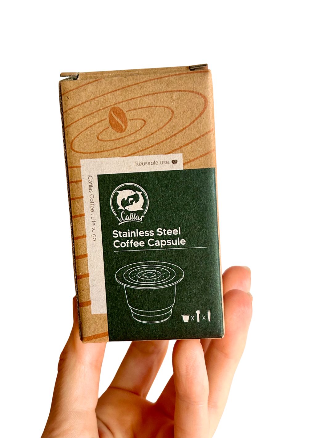 Hand holding a  stainless steel reusable nespresso capsule package against a white background